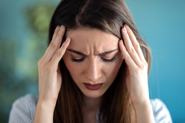 Woman holding her temples with a worried expression.